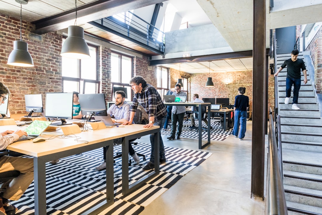 Two colleagues discussing work in an open-plan technology office