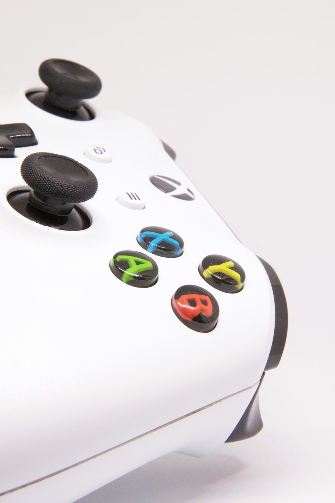 Close-up of a white video game controller with blue and green button details