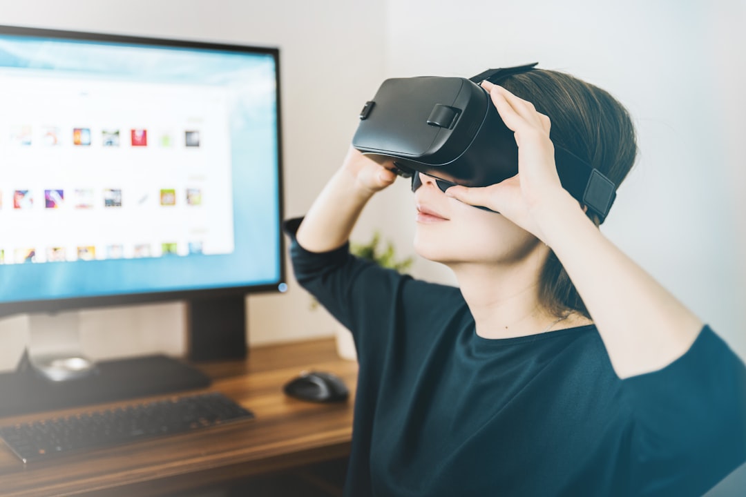 Woman using a virtual reality headset beside a computer workstation